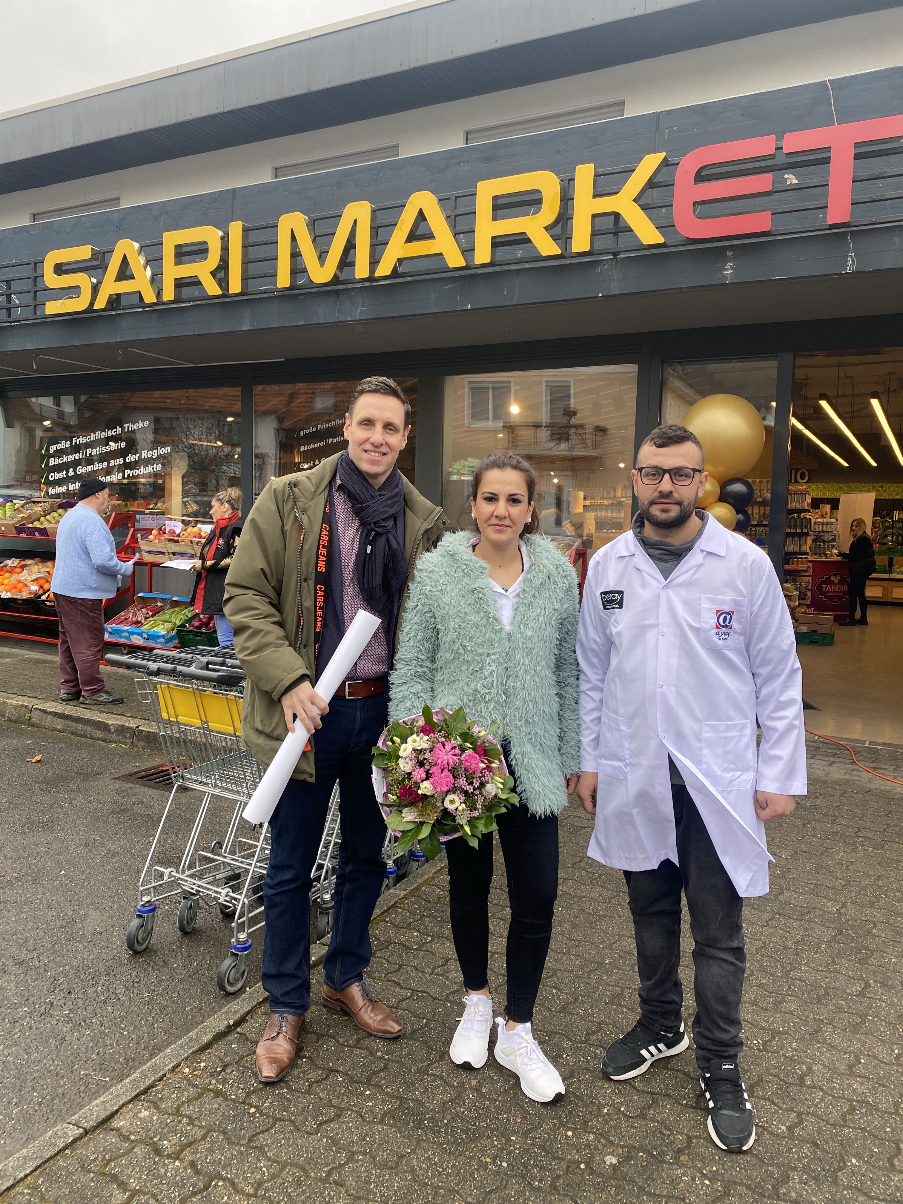 
    
            
                    Bürgermeister Förster überreicht einen Blumenstrauß an Familie Sari, die neuen Geschäftsinhaber des Sari Market
                
        
